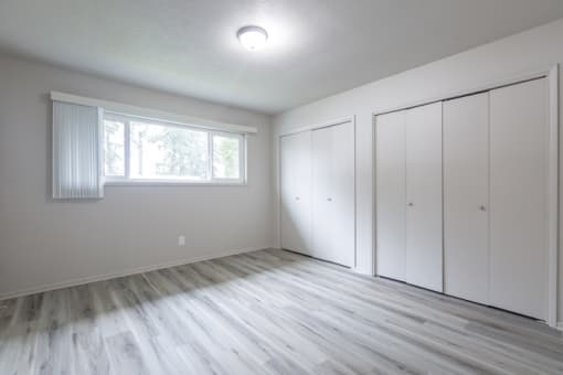 an empty bedroom with white walls and white closets