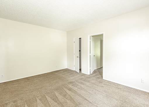 A room with carpeted floor and two doors.