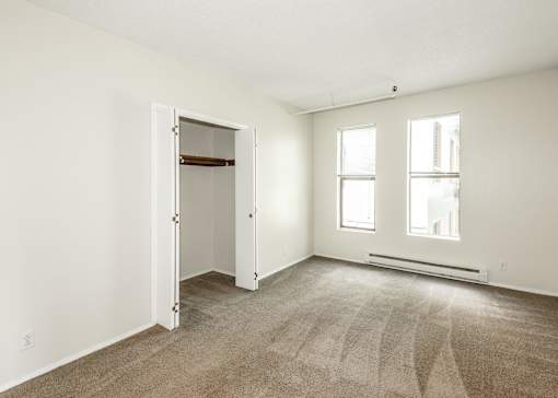 A room with a carpeted floor, two windows, and a door.