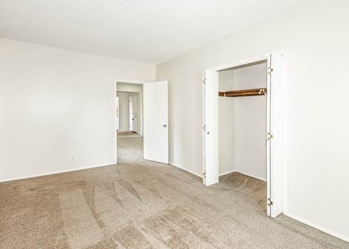 A room with a carpeted floor and two open doors.