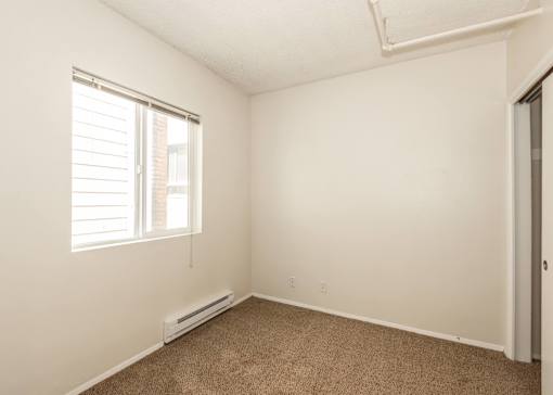 A room with a window and a carpeted floor.