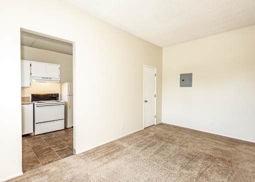 A room with a carpeted floor and a wall-mounted air conditioner unit.