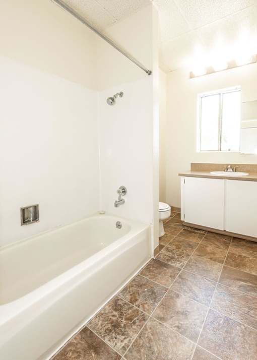 A white bathroom with a tiled floor and a bathtub.
