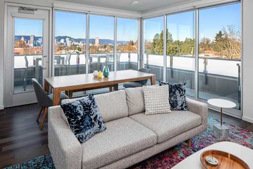 A living room with a grey couch and a table with a vase of flowers on it.