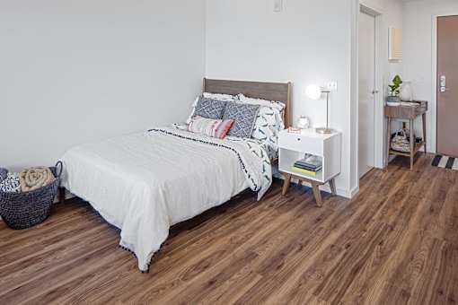 A bedroom with a bed, nightstand, and basket.