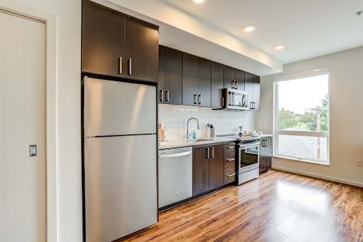 A modern kitchen with dark wood cabinets and stainless steel appliances.