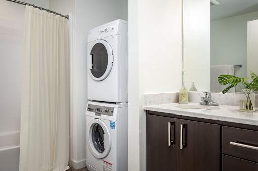 A white front loading washing machine in a bathroom.
