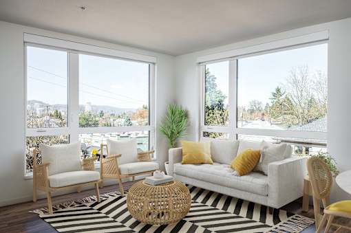 A living room with a white couch, two chairs, and a woven coffee table.
