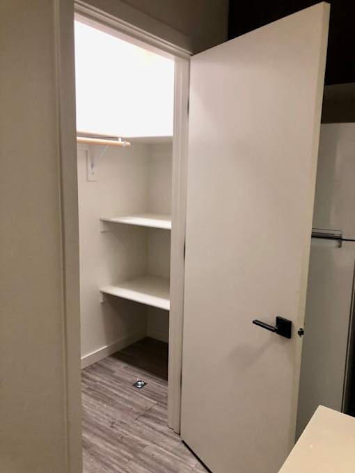 A white closet with a black handle and a shelf.