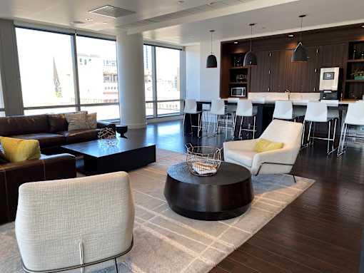 A modern living room with a brown sofa, white chairs, and a coffee table.