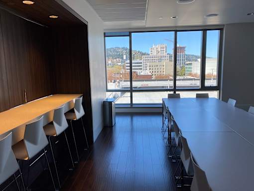 A conference room with a long table and chairs facing a window with a view of a cityscape.