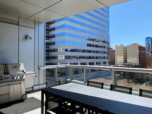 A barbecue grill is on a patio overlooking a cityscape.