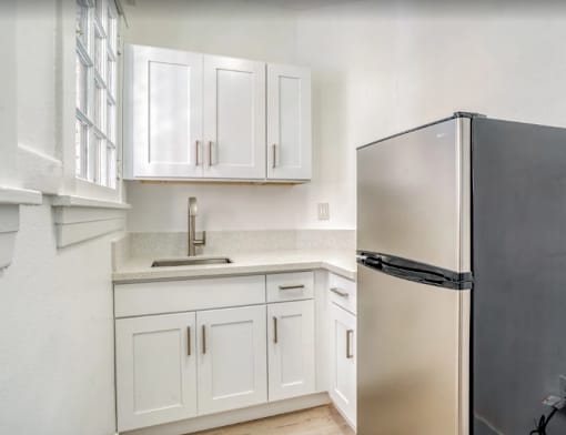 A black refrigerator sits next to a sink in a kitchen with white cabinets at Clay & Tiffany, Portland, 97201