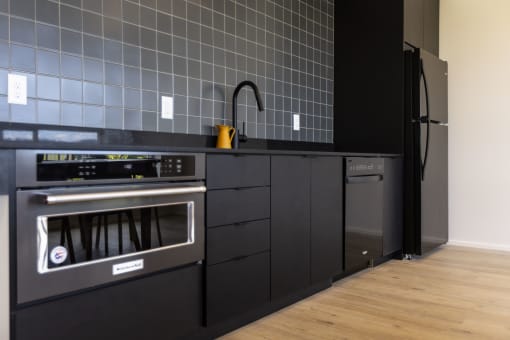 a kitchen with black cabinets and a stainless steel oven and sink at Shift, Oregon