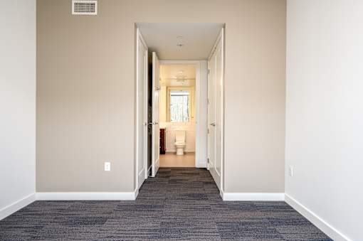 A hallway with a carpeted floor and a doorway leading to a bathroom.