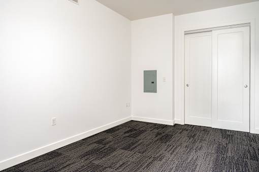 A room with a grey carpet and a white door.