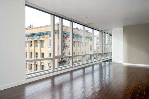 A room with a large window overlooking a street with buildings.
