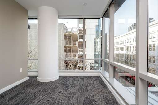 A room with a large white column and a view of the city through the windows.