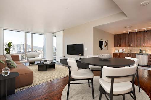 A modern living room with a brown sofa, a black coffee table, and a flat screen TV.