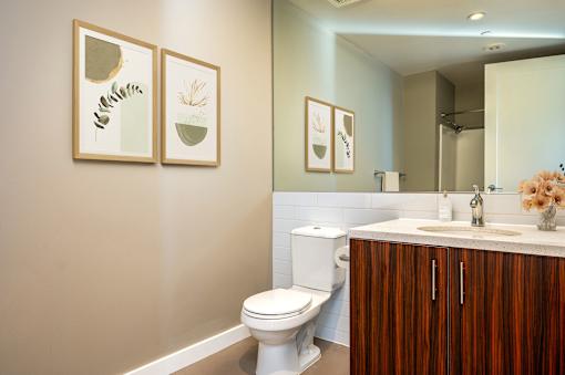 A bathroom with a toilet, sink, and framed pictures on the wall.