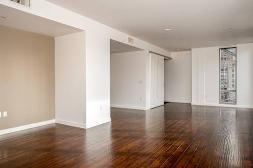 A large empty room with wooden floors and white walls.