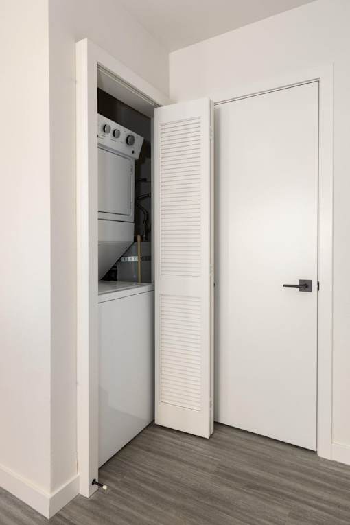 A white door is open to a kitchen with a white oven.