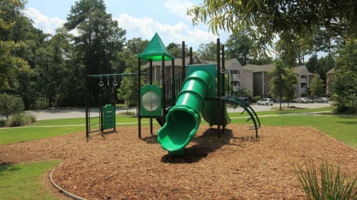 a playground with a green slide and monkey bars
