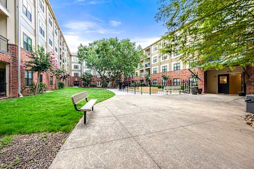 A bench is situated on a concrete area in front of a building.
