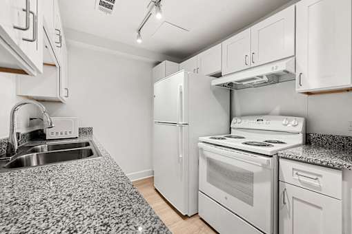 A kitchen with white appliances and a granite countertop.