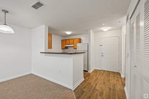 A kitchen area with white walls and wooden flooring.