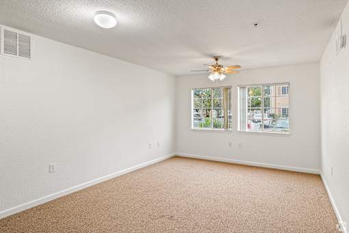 A room with a ceiling fan and carpeted floor.