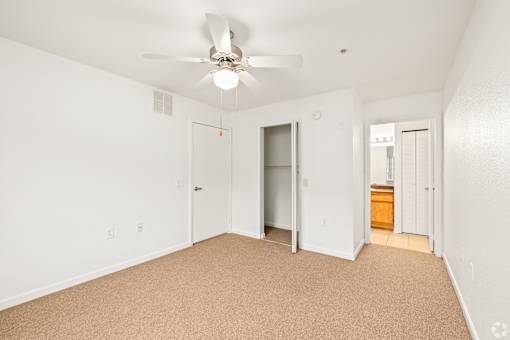 A room with a ceiling fan and carpeted floor.