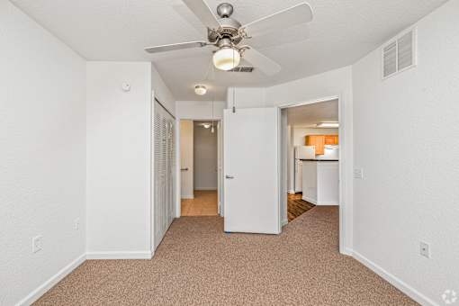 A room with a ceiling fan and carpeted floor.
