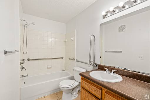 A white bathroom with a brown counter top and a white toilet.