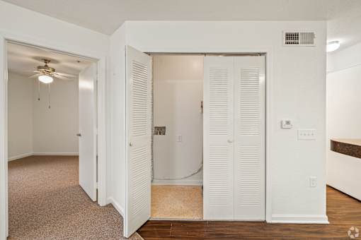 A white interior room with a doorway leading to another room.