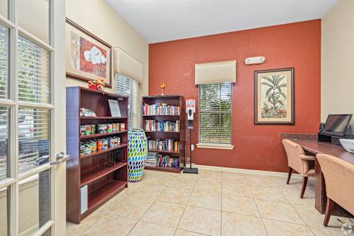 A room with a red wall and a bookcase filled with books.