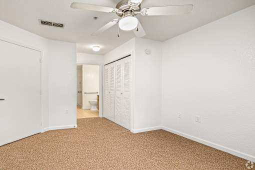 A room with a ceiling fan and carpeted floor.