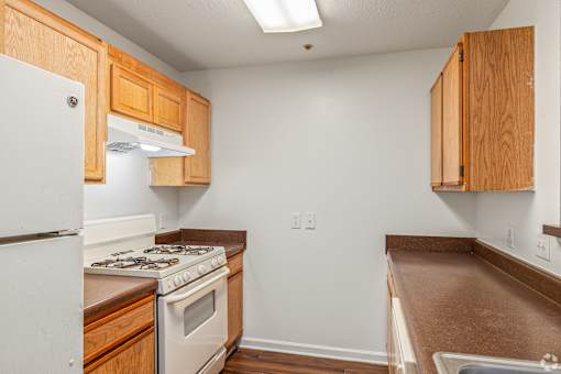 A kitchen with wooden cabinets and a white refrigerator.