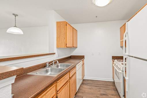 A kitchen with a white refrigerator, brown countertops, and wooden cabinets.
