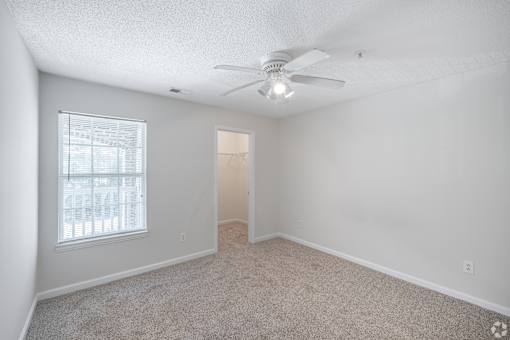 A room with a ceiling fan and carpeted floor.