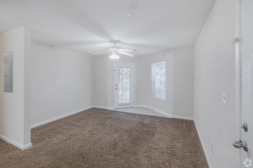 A room with a carpeted floor and a ceiling fan.