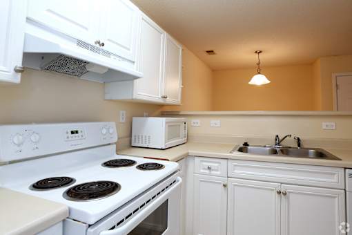 A white stove and oven in a kitchen with white cabinets.