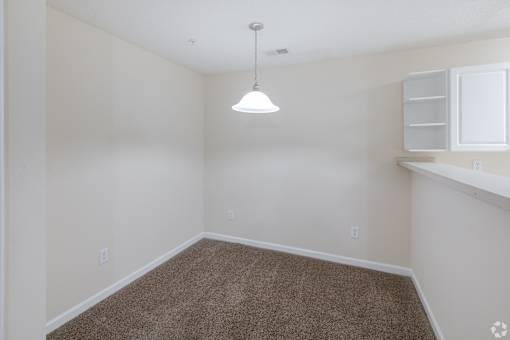 A room with a carpeted floor and a single light fixture.