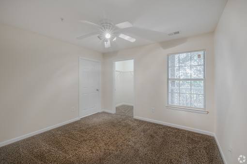 A room with a ceiling fan and carpeted floor.