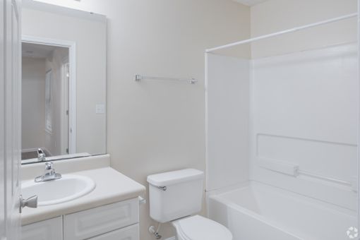 A white bathroom with a toilet, sink, and bathtub.