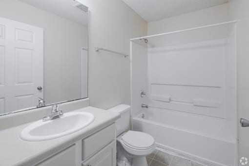 A white bathroom with a toilet, sink, and bathtub.
