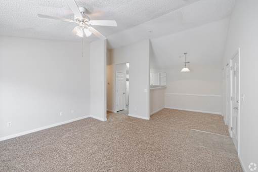 A room with a ceiling fan and carpeted floor.