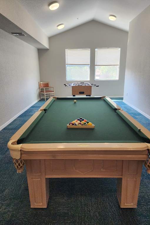 A pool table with a green felt cloth and a set of pool balls on it.