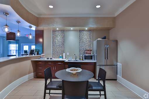A kitchen with a table and chairs in the foreground and a refrigerator in the background at The Bristol Apartments, Greenville, 29601