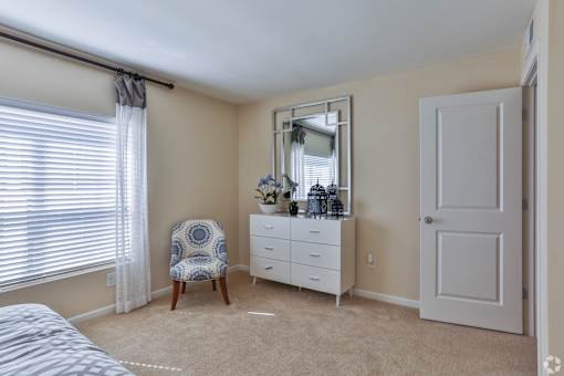 A bedroom with a bed, chair, and dresser at The Bristol Apartments, Greenville, South Carolina
